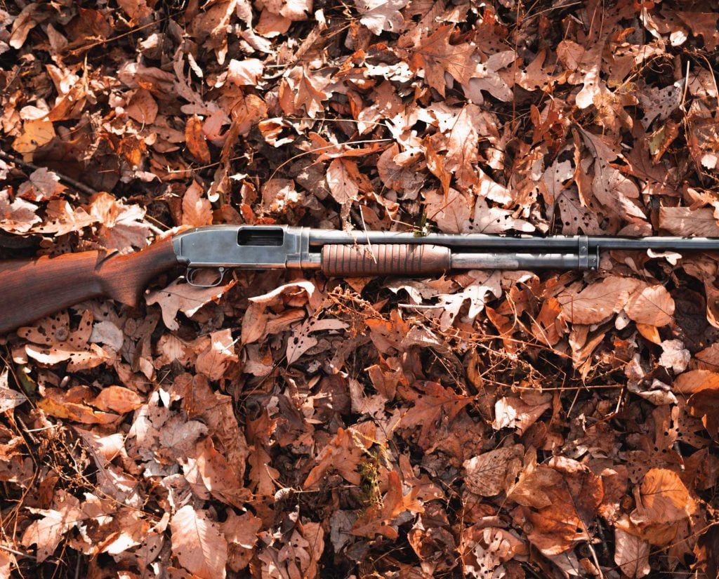 A Model 12 shotgun laid out on the ground 
