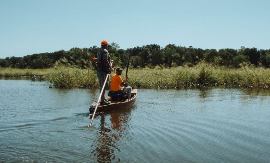 A bird hunter on skiff looking for sora rails.