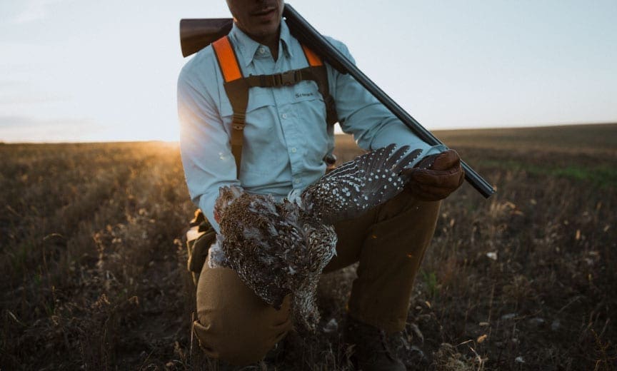 A sharp-tailed grouse hunter with a shogun and bird.